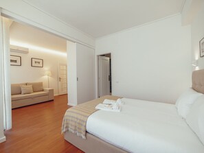 A hotel room with a bed, a sofa, and a door leading to a bathroom. - Apartment  by Interhome (Porto)