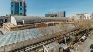 Ein modernes Gebäude mit großer Glasfassade und flachem Dach, ausgestattet mit Solarpanels.