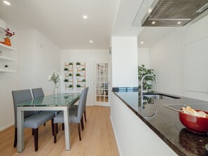 A modern kitchen with a glass dining table, grey chairs, and a red bowl on the counter. - Apartment  by Interhome (Porto)