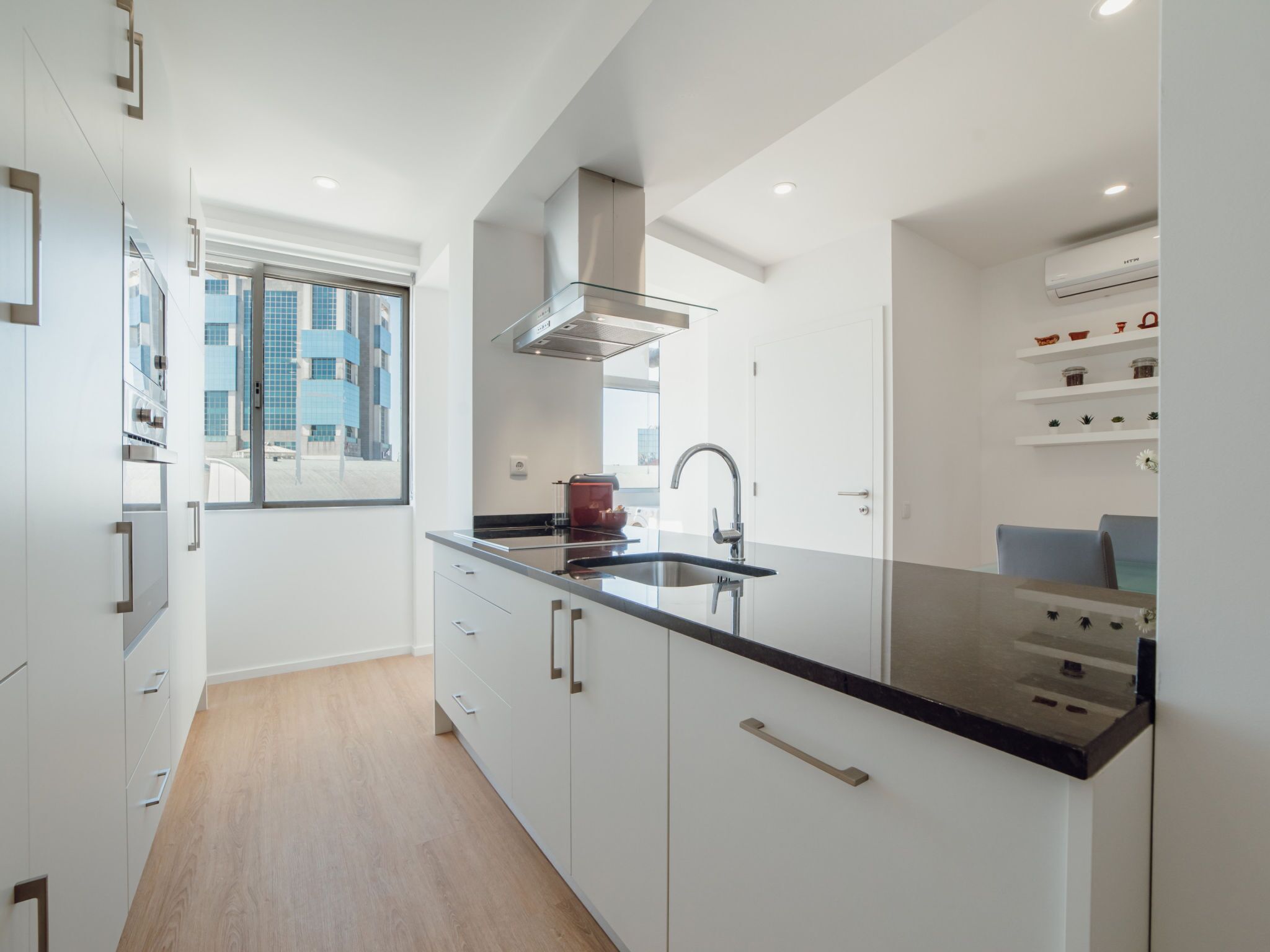 A modern kitchen with a large window, stainless steel appliances, and a black countertop.