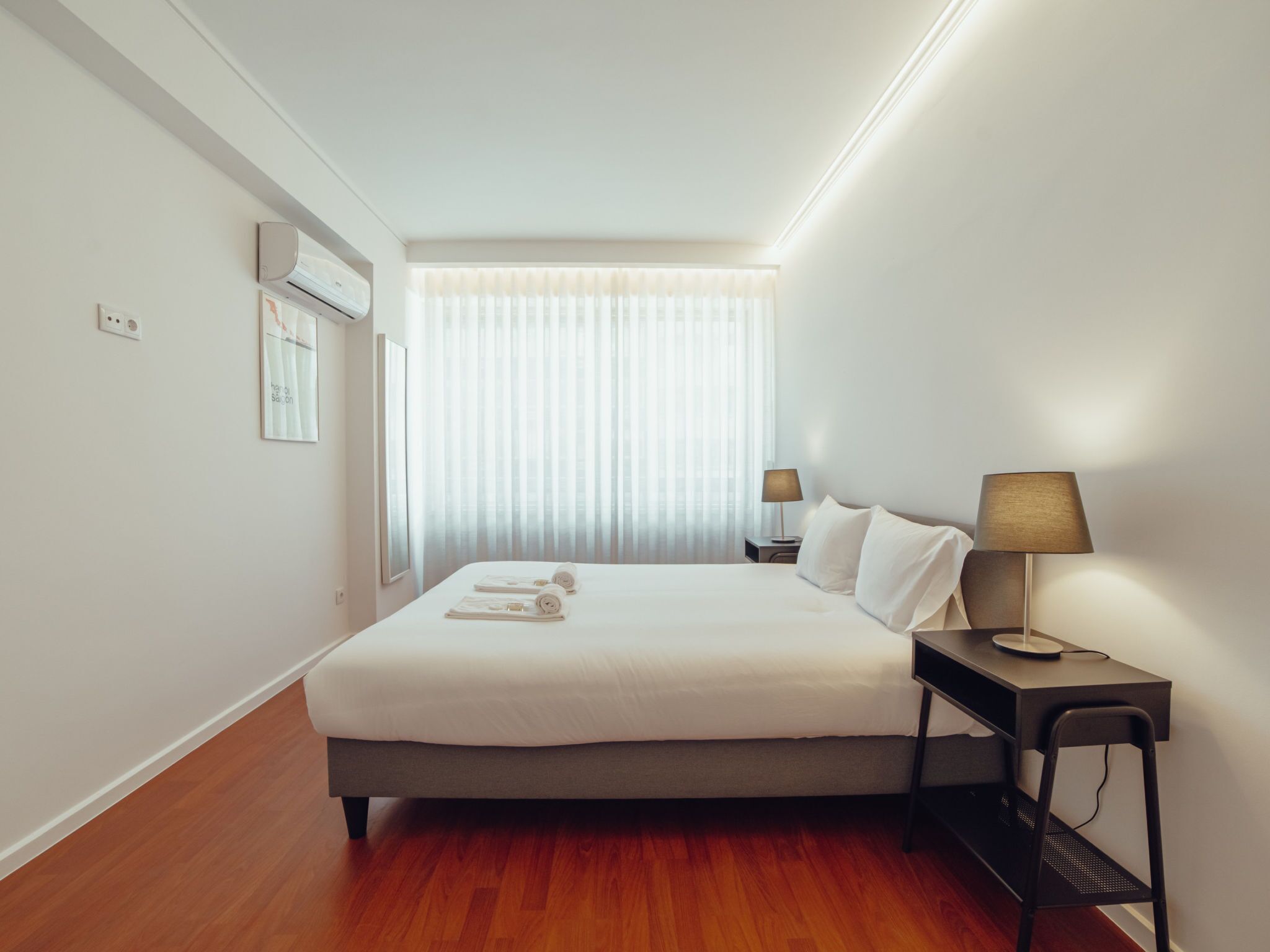 Une chambre d’hôtel avec un lit, des tables de chevet, une lampe et une fenêtre avec des rideaux.