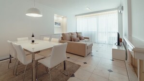 Ein modernes Wohnzimmer mit Essbereich, einer Couch und einem Fernseher.
