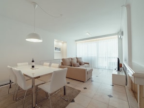 A modern living room with a dining area, a sofa, and a TV. - Apartment  by Interhome (Porto)