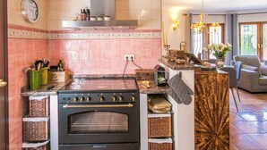 A kitchen with a stove, oven, and a dining area with a sofa and table. - Villa Talia by Interhome (Moraira)