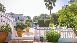A white building with a curved staircase leading to a balcony, surrounded by potted plants and a white fence. - Villa Talia by Interhome (Moraira)