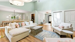 A spacious living room with a high ceiling, a dining area, and a view of the outdoors. - Renovated Sea Pines Home Near Beach (Hilton Head Island)