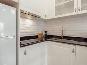 A modern kitchen with white cabinets, black countertops, and a stainless steel sink. - Apartment  by Interhome (Porto)