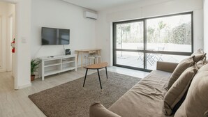 Ein modernes Wohnzimmer mit Flachbildfernseher, einem kleinen Holztisch und einer Couch.