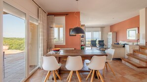 Un comedor amplio con una mesa grande, sillas blancas y vistas al exterior.