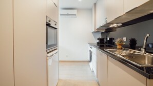 Ett modernt kök med vitvaror i rostfritt stål, en inbyggd ugn, en diskmaskin och en stor diskho.