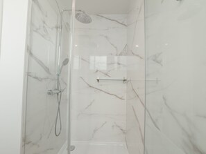 Eine Duschkabine mit Handbrause und Wandarmatur.