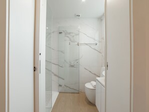 Ein modernes Badezimmer mit Duschkabine aus Glas, Toilette und Waschbecken.