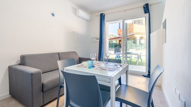 A dining area with a table, chairs, and a sofa. - Affittimoderni Castelsardo - Our Villa (Castelsardo)