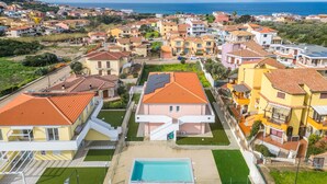 A residential area with a swimming pool, houses with red-tiled roofs, and a view of the sea. - Affittimoderni Castelsardo - Our Villa (Castelsardo)