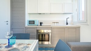 A compact kitchen with a microwave, oven, sink, and cabinets. - Affittimoderni Castelsardo - Our Villa (Castelsardo)