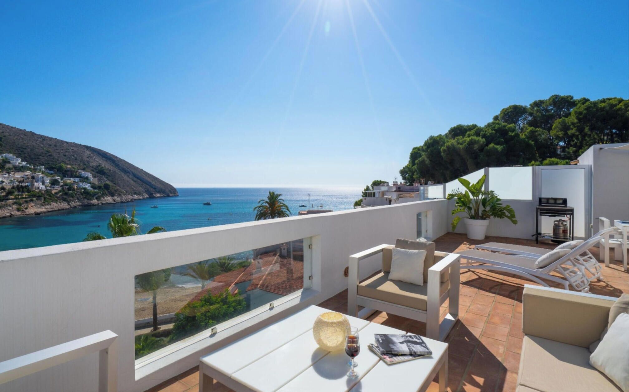 Une terrasse avec vue sur la mer, des meubles d’extérieur et une plante en pot.