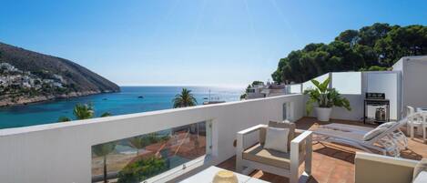 Une terrasse avec vue sur la mer, des meubles d’extérieur et une plante en pot.