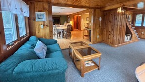 L’intérieur d’un chalet en bois comprend un canapé, une table à plateau en verre, un escalier et un coin repas.