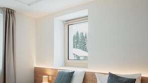 A hotel room with two beds, a window with a view of trees, and a wooden headboard. - Alpine Apartments, (San Bernardino), by Interhome (San  Bernardino)
