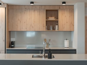 Een moderne keuken met houten kastjes, een roestvrijstalen spoelbak en een koffieapparaat.