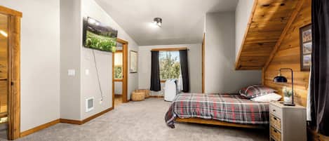 Et soveværelse med seng, sengebord, lampe og et vindue med gardiner.