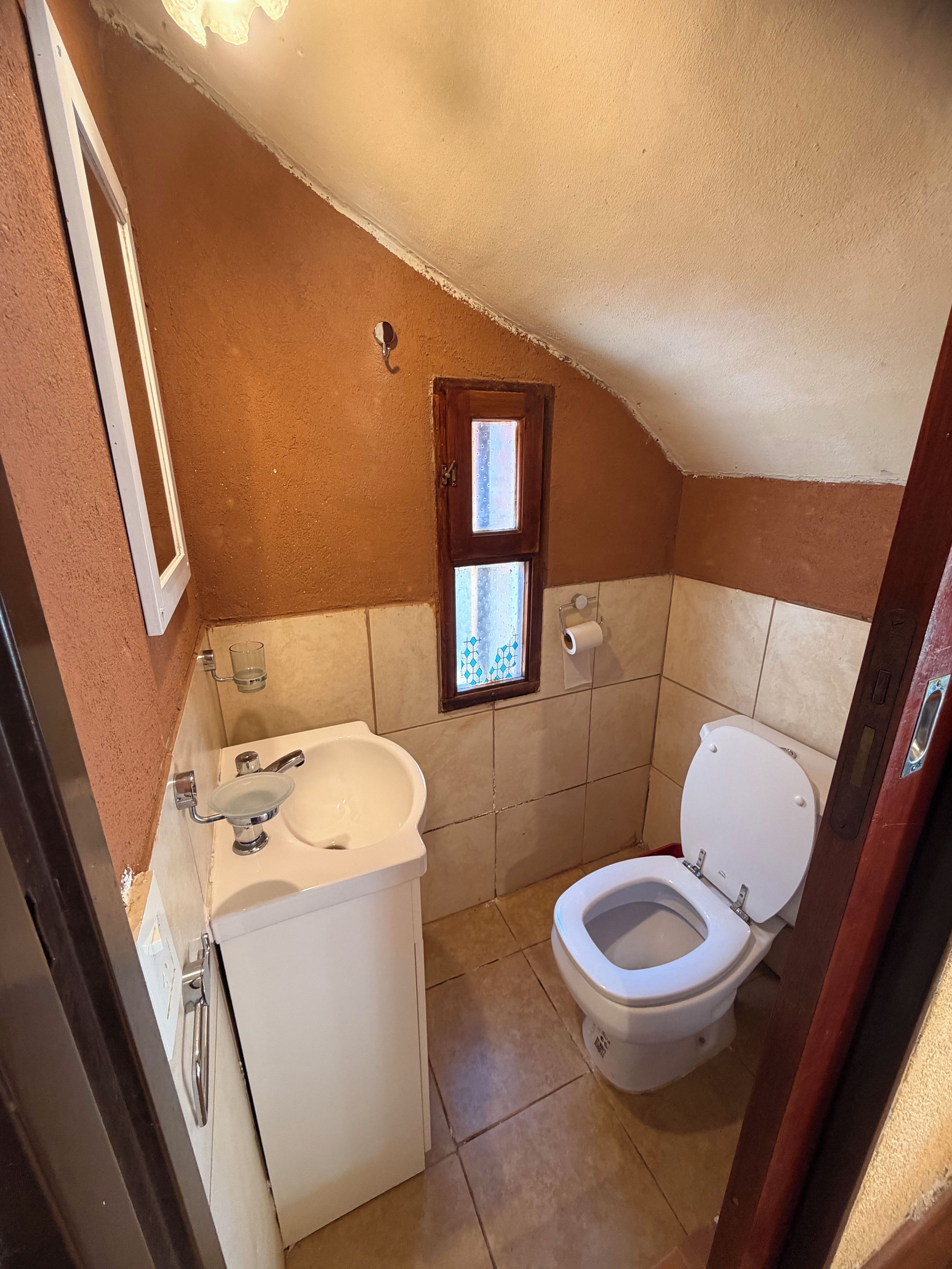A small bathroom with a sink, toilet, and a window.