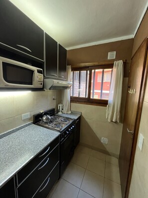 A compact kitchen with a microwave, stove, and cabinets.