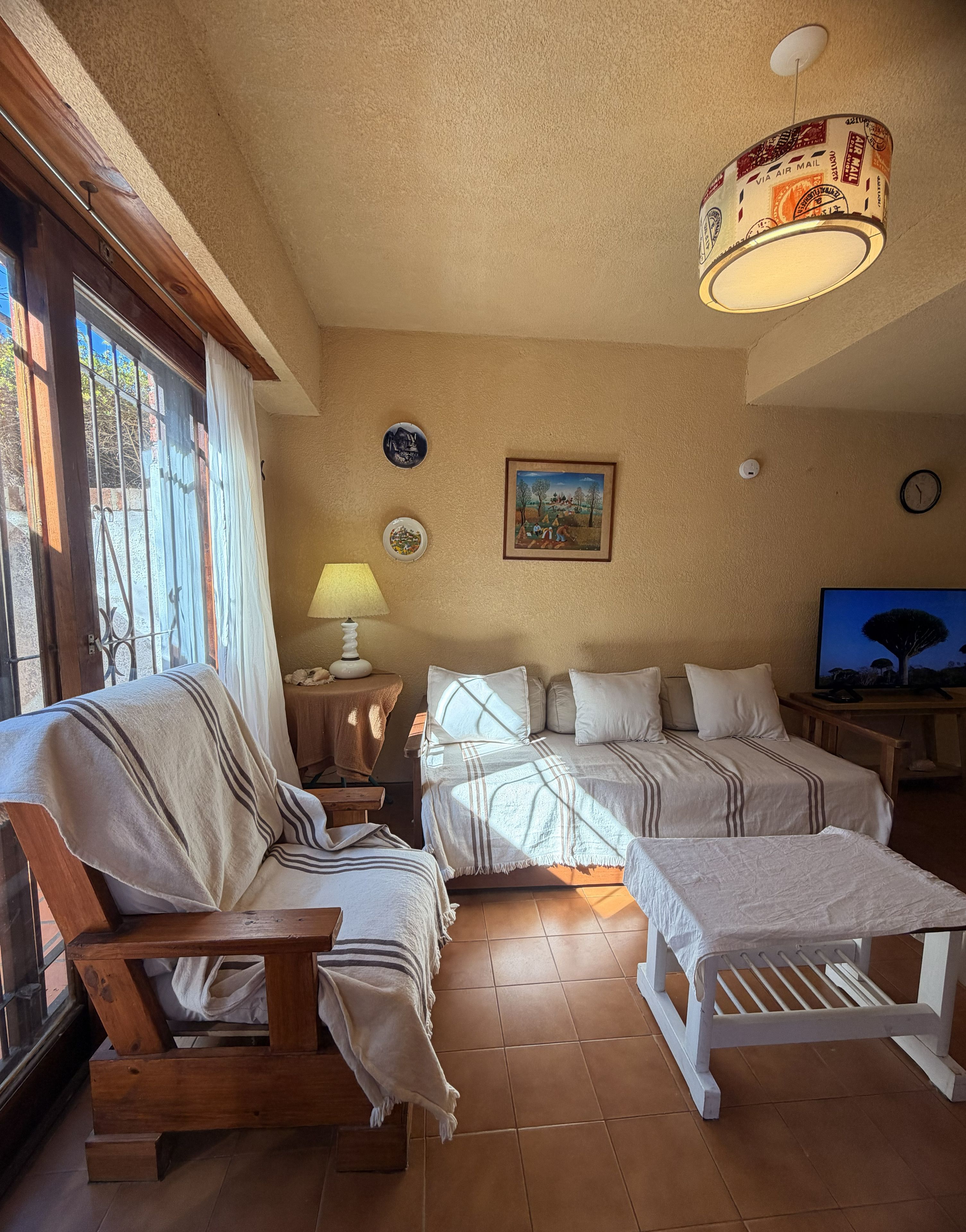 A cozy room with a sofa, a bed with a canopy, a lamp, a painting, and a television.