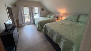 Quarto com duas camas, uma escrivaninha, um abajur e um ventilador de teto.
