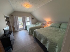 Ein Schlafzimmer mit zwei Betten, einem Schreibtisch, einer Lampe und einem Deckenventilator.