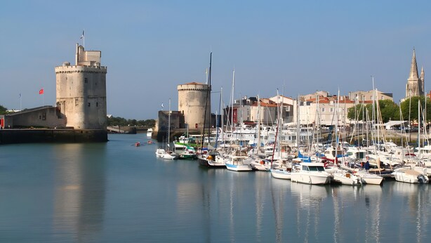 Un port de plaisance avec des bateaux amarrés, un château et une tour.