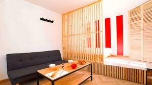 Un salon moderne avec un canapé, une table basse en bois et un élément de séparation composé de lattes verticales.
