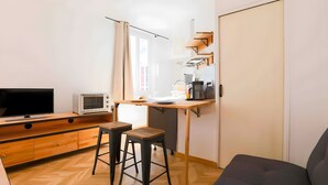 Une cuisine de taille réduite, équipée d’un téléviseur, d’un four à micro-ondes et de meubles en bois.
