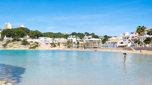 A coastal town with buildings along the beach, clear blue water, and a person standing in the water. - Villa Lorenza by Interhome (Moraira)
