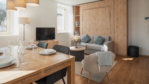 Una sala moderna con una mesa de comedor de madera, sofá gris y televisor.
