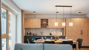 Une cuisine moderne avec des meubles en bois, une table à manger pour quatre personnes et un canapé agrémenté de coussins turquoise.