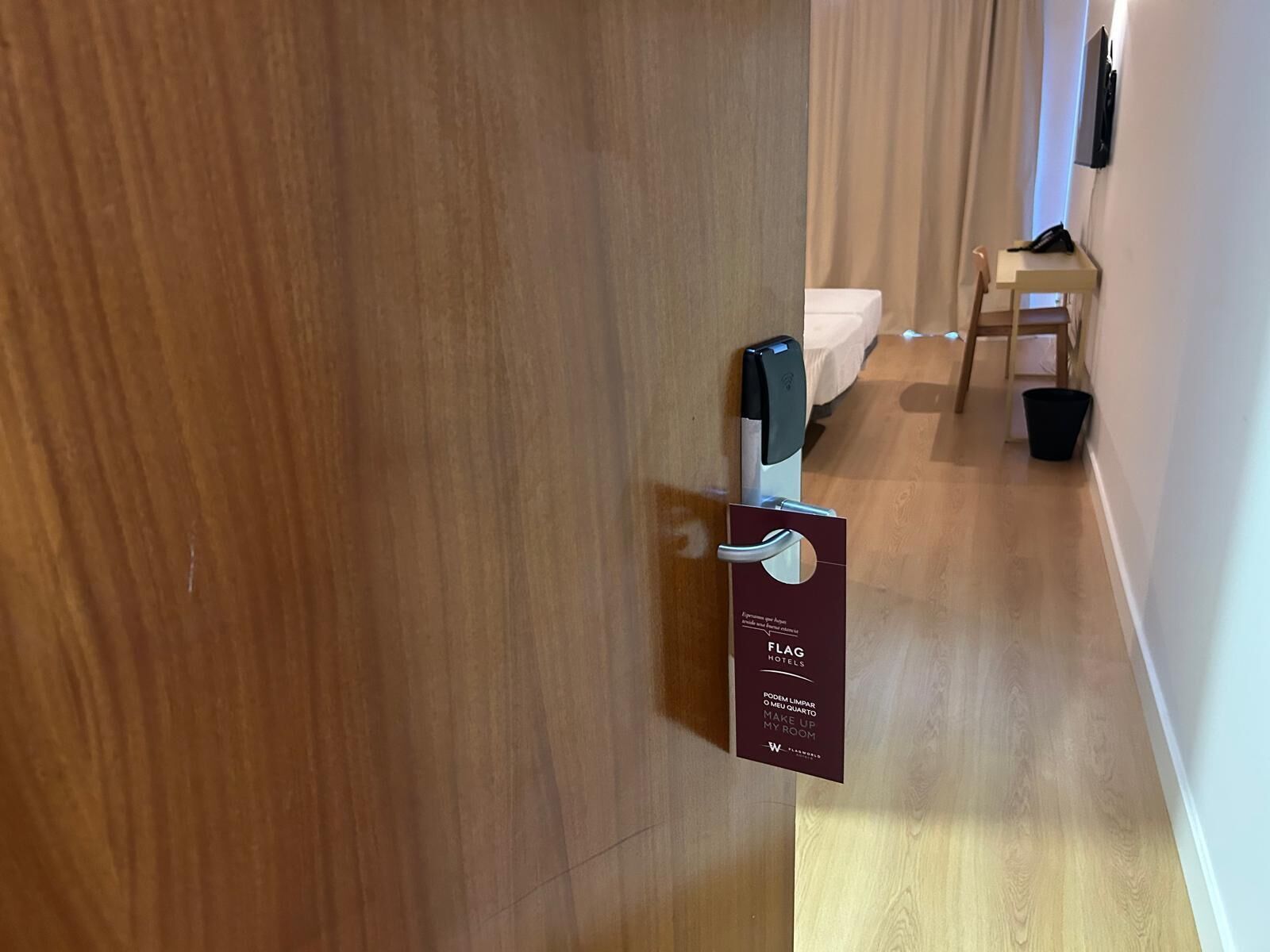 A wooden door with a keycard lock and a sign indicating room service availability.