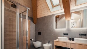 Un baño moderno con ducha envuelta en vidrio, un bidé y un tocador con un espejo grande.