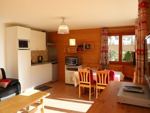 A compact kitchen with a microwave, toaster, and a small refrigerator. There is a dining area with a table and chairs, and a window with curtains. - Petit Nid Douillet au Coeur de Salvan by Interhome (Salvan)