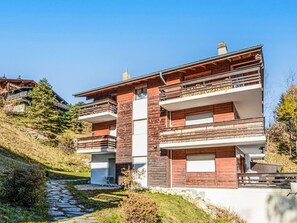 Ein modernes, zweistöckiges Haus mit einer Steinaußenwand, einem Balkon und einem Kiesweg, der zum Eingang führt.