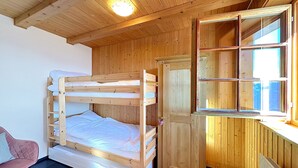 Un lit superposé avec une tête de lit en bois, un petit bureau avec un miroir et une chaise rose.