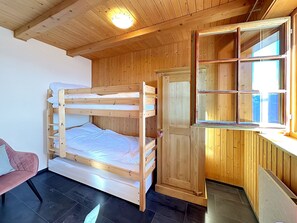 Ein Etagenbett mit Holz Kopfteil, ein kleiner Schreibtisch mit Spiegel und ein pinkfarbener Stuhl.