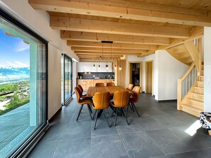 A modern kitchen with wooden beams, a dining area with a large table and chairs, and a view of a landscape through large windows. - My Mountain Paradise in the Swiss Alps by Interhome (Grône-Loye)