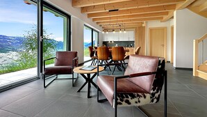 Un interior moderno con zona de comedor, ventanas amplias y vistas al exterior.