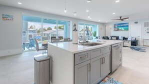 Una cocina moderna con una isla grande, un comedor con sillas y vistas al exterior.
