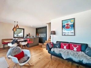 Ein modernes Wohnzimmer mit Sofa, Sessel, Essbereich und Küche.