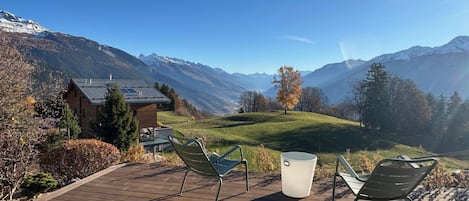 Une terrasse en bois avec des sièges extérieurs et une vue sur un paysage montagneux.