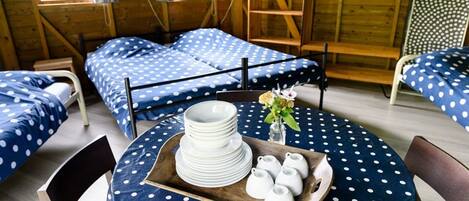 A room with two beds, a round table with a polka dot tablecloth, and a tray with plates and teapots.