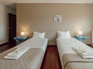 Une chambre d’hôtel avec deux lits simples, chacun étant équipé d  ’un oreiller et d’une table de chevet avec une lampe.
