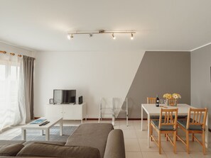 Una sala de estar moderna con un sofá, una mesa de centro, un televisor y un comedor con una mesa y sillas.